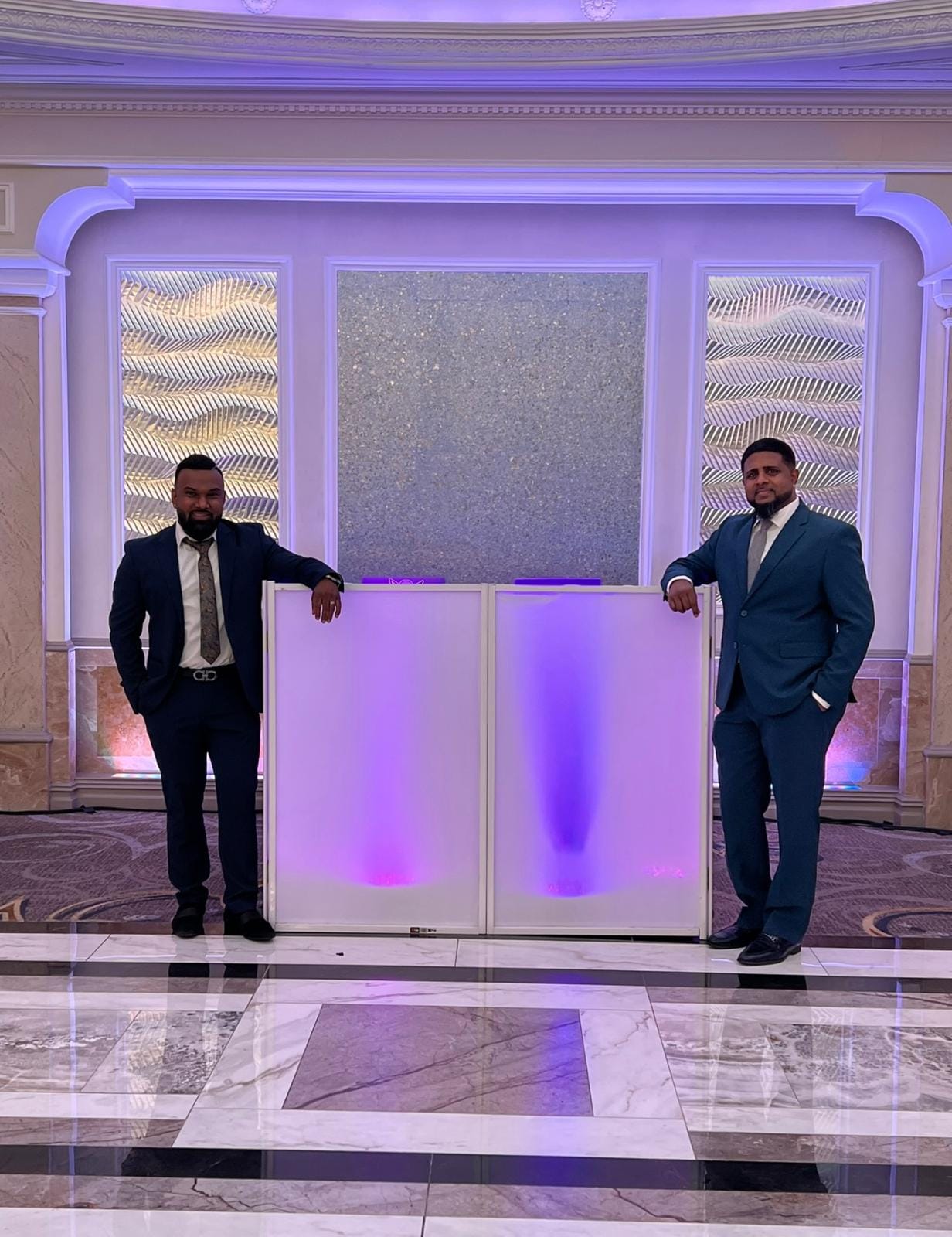 Two of the crew beside the white LED DJ booth in a grand ballroom